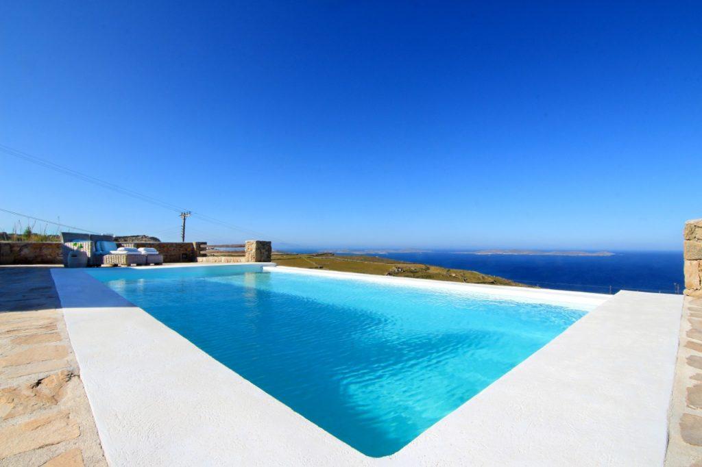 view of the calm blue sea from the pool in the courtyard of the villa