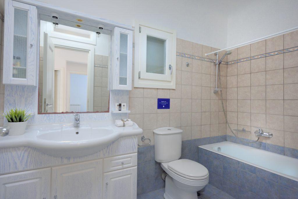 bathroom with gray cream tiles and white large bathtub