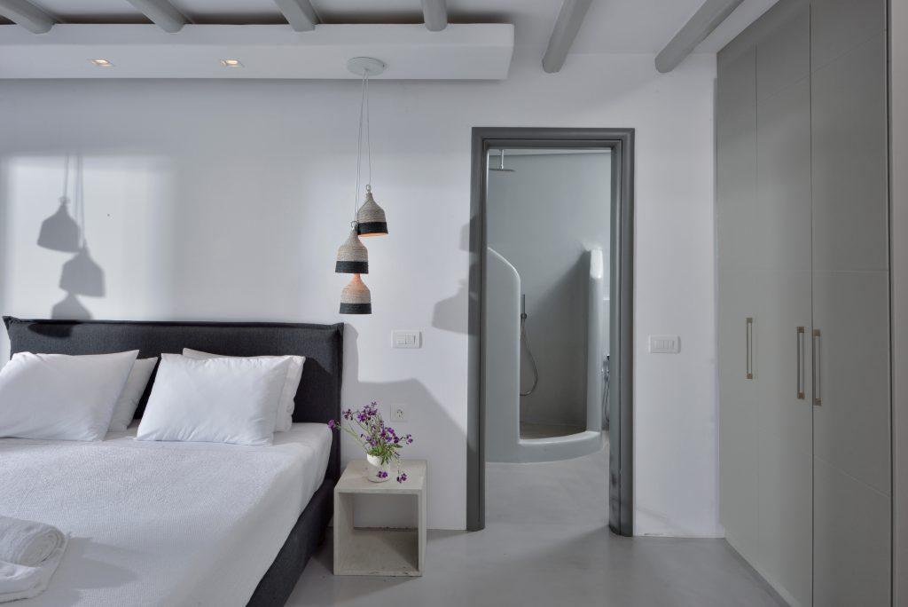 white walls of the room with a comfortable gray bed and a wooden bedside table decorated with flowers