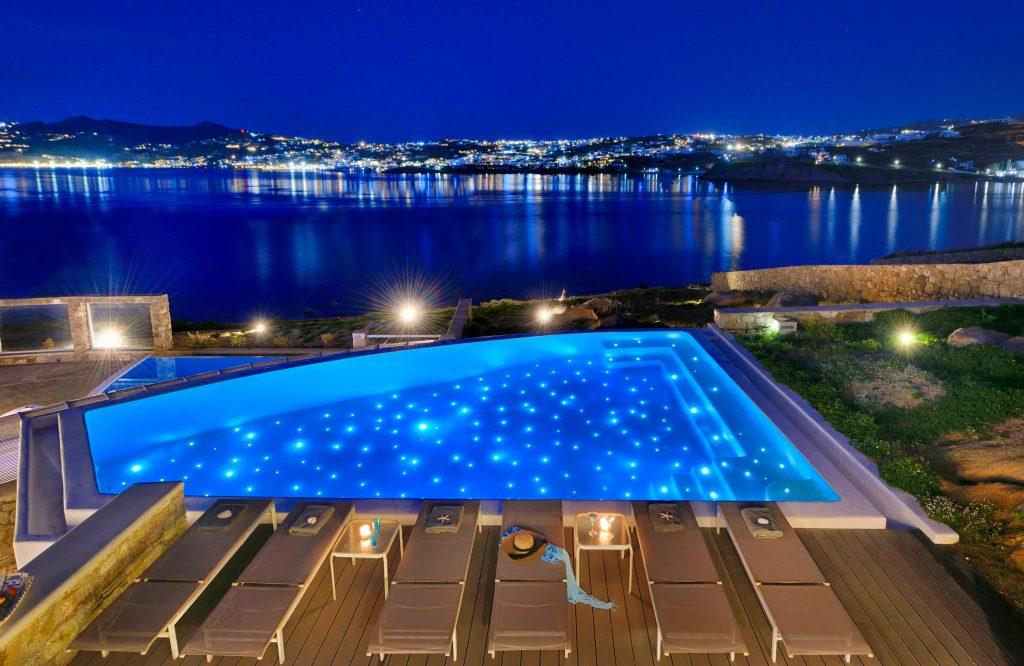 view of the illuminated city and the glistening sea from the illuminated pool ideal for a romantic night under the stars