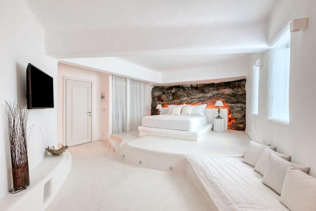 bedroom with double bed and specially designed stone wall that is lit