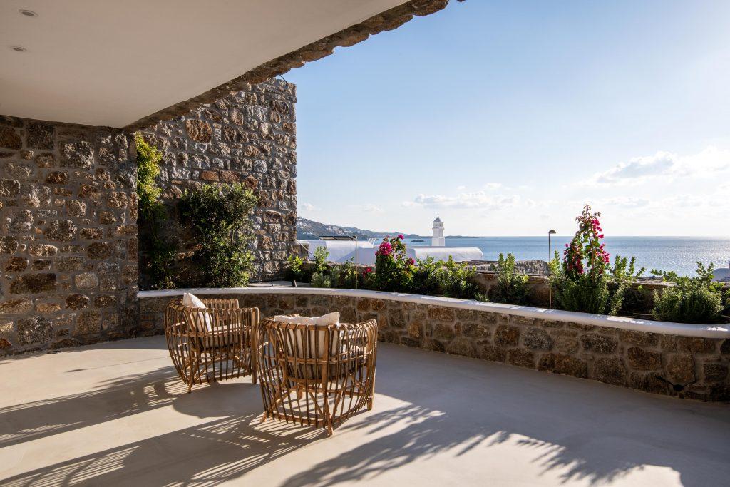 balcony surrounded by a stone fence decorated with flowers overlooking the beautiful sea