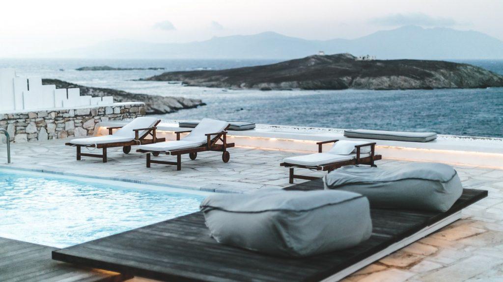 wooden deck chairs with comfortable white pillows that fit perfectly next to the stone fence